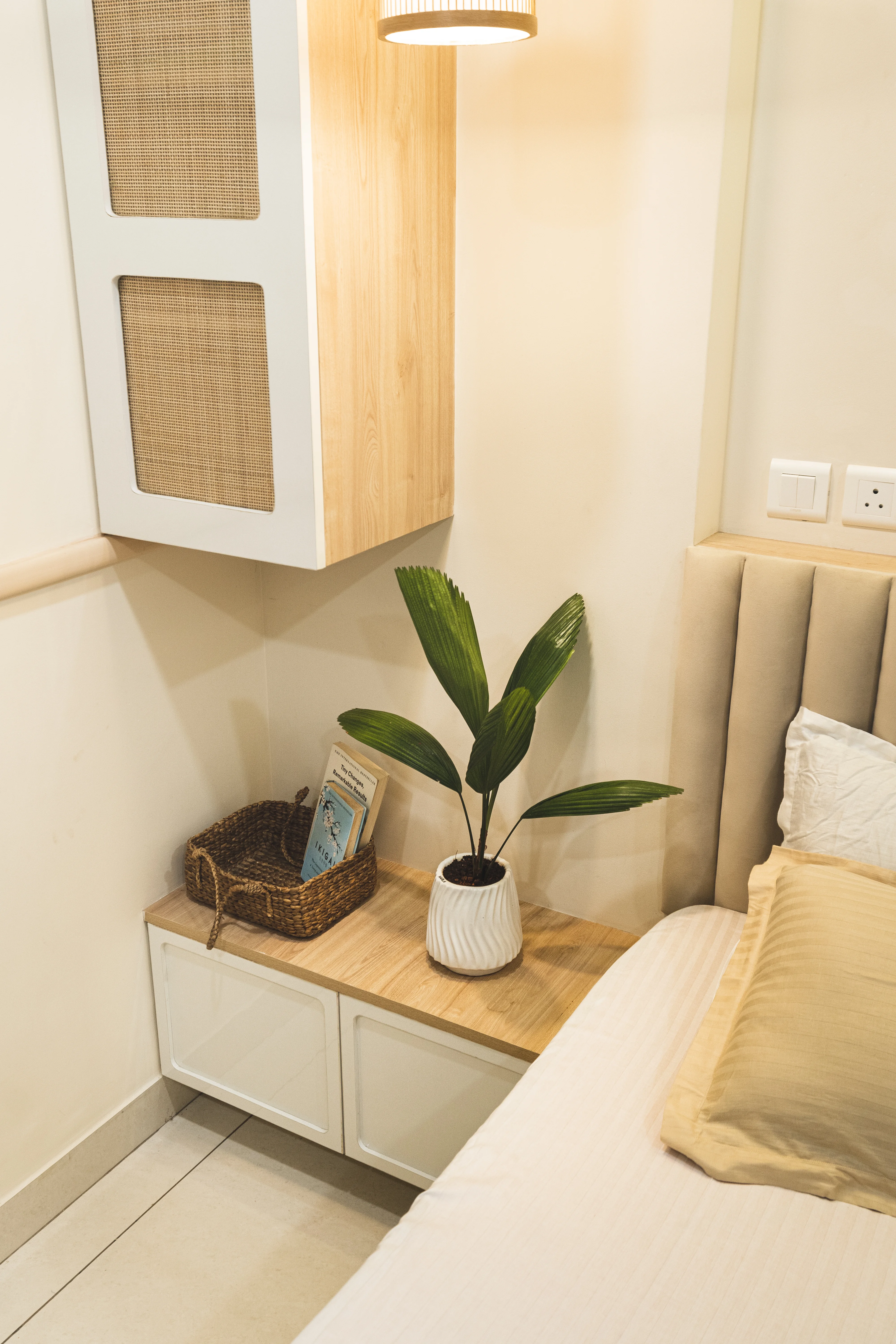 A stylish bedroom featuring a bed, dresser, and house plant, designed with curves and minimal aesthetics for South Indian homes.