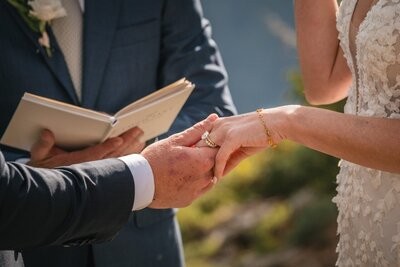 Close-up of the wedding ring exchange, with the officiant's open book behind their hands.