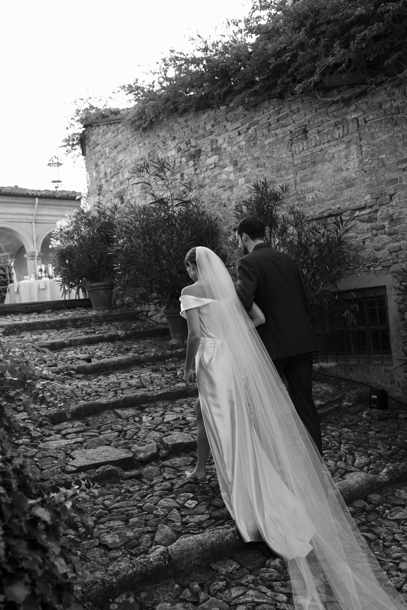 Sposa con velo lungo e sposo nel cortile medievale del Castello di Scipione, reportage di matrimonio in bianco e nero