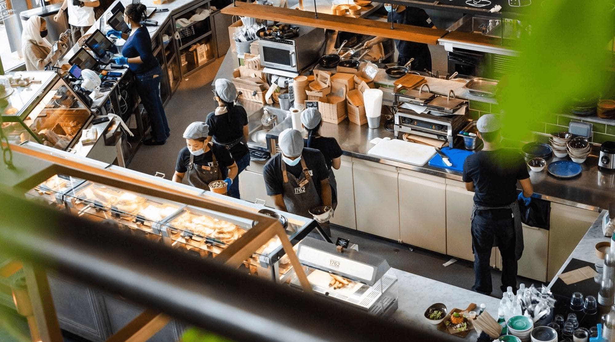 A busy breakfast place in Dubai that features a full cafe and bakery with lots of employees and customers.