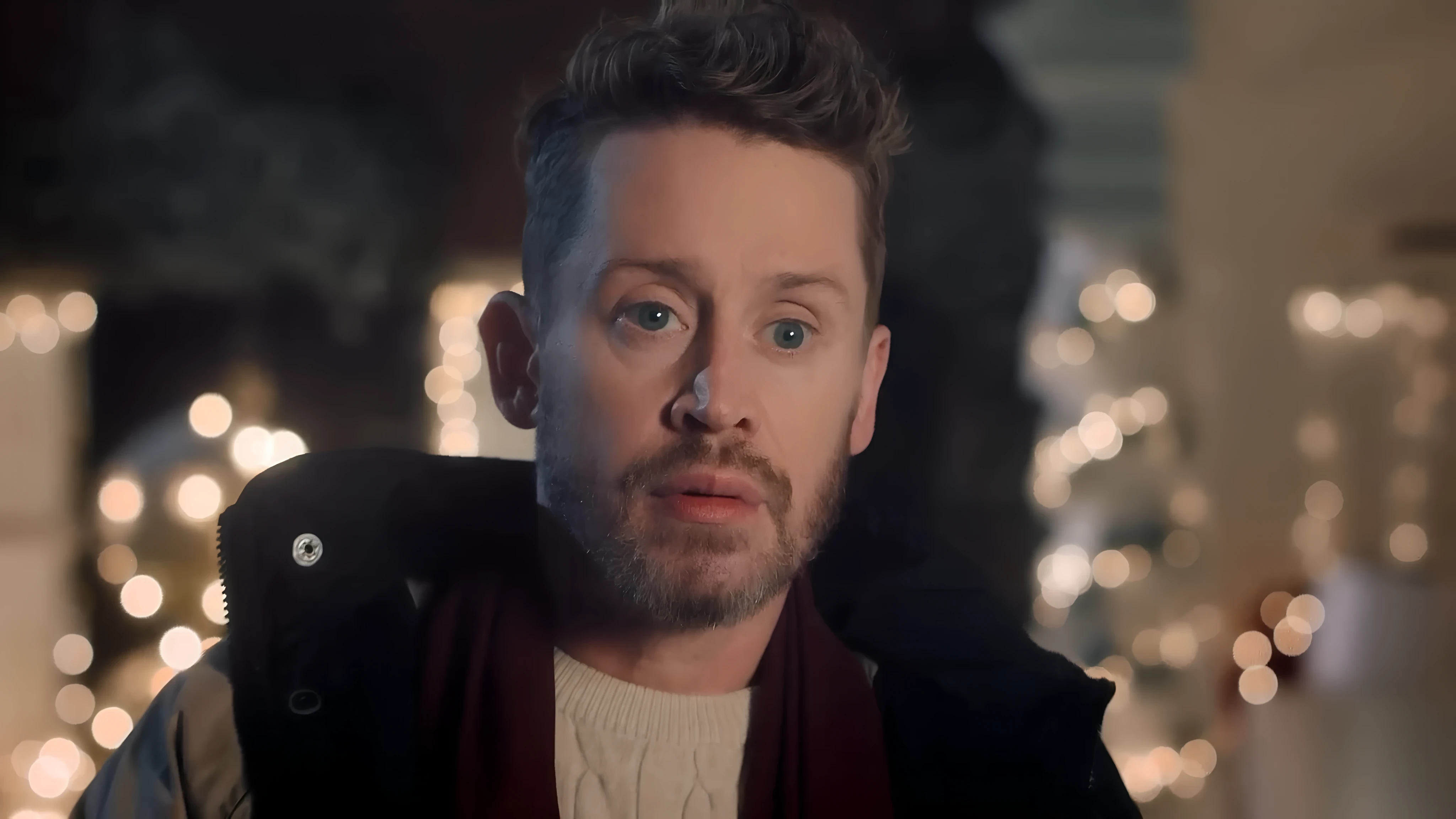 Macaulay Culkin, surrounded by soft lights, looking directly at the camera with a thoughtful expression.