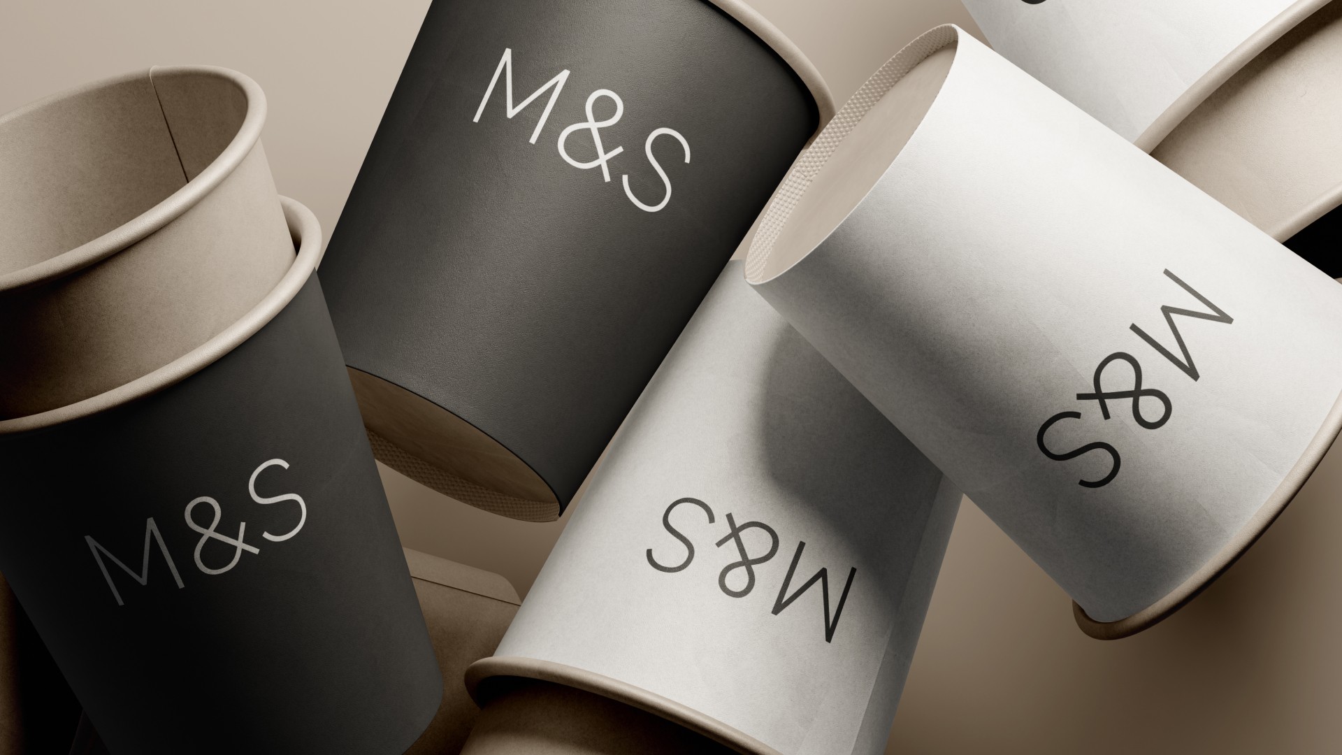 A high-end studio shot of M&S branded coffee cups, showing the simple and elegant packaging design in both black and white with the M&S logo.