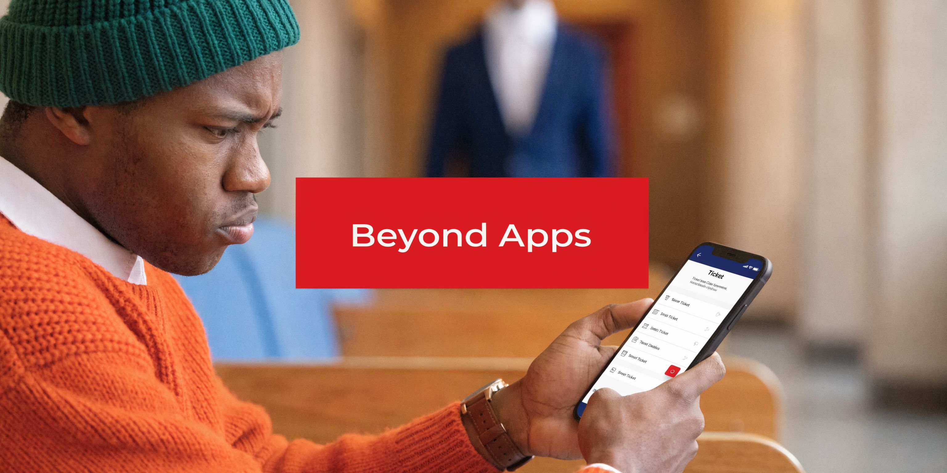 A man wearing an orange sweater and a green beanie looks at a mobile phone screen displaying tickets.