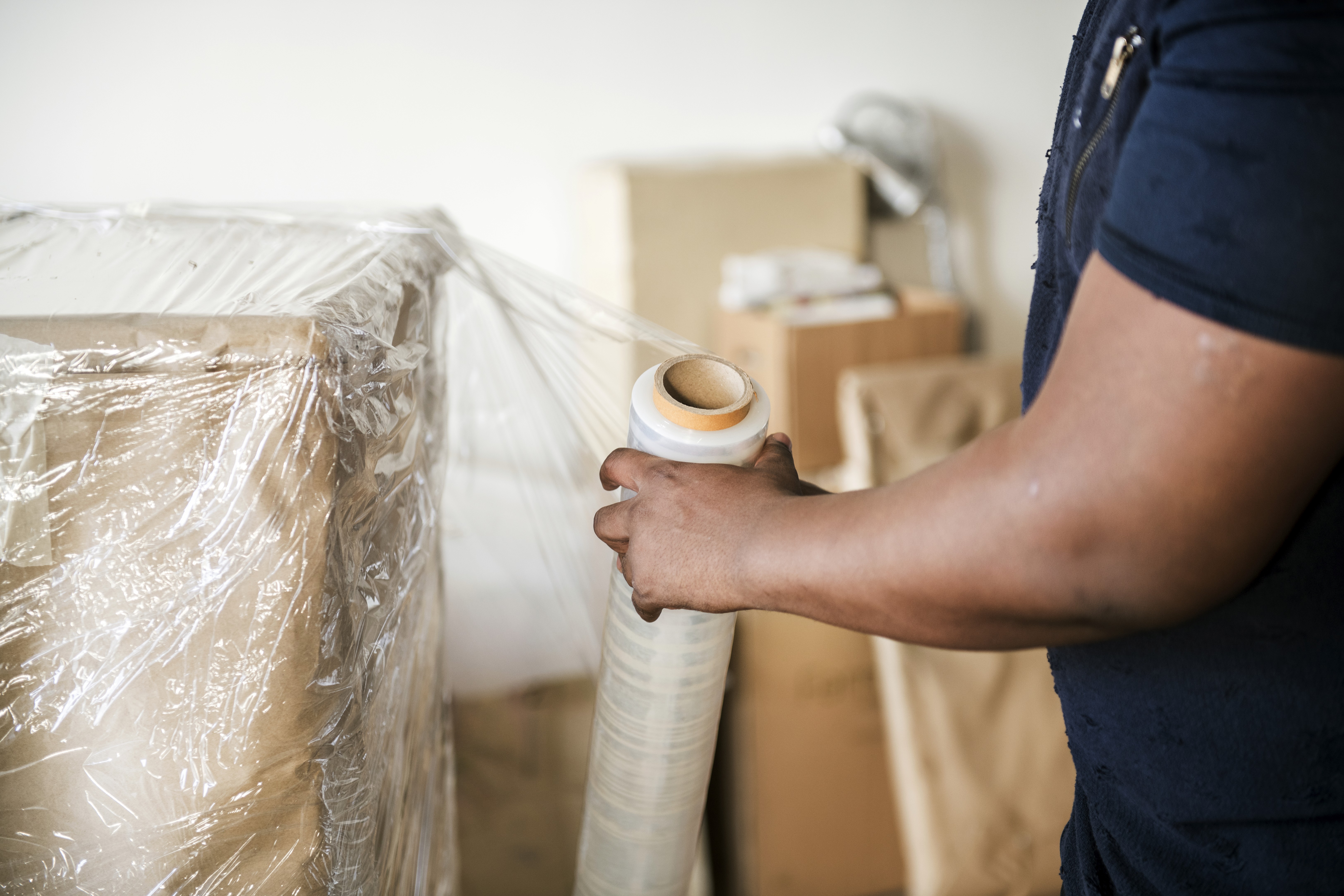 A man is bubble wrapping a box of TV.