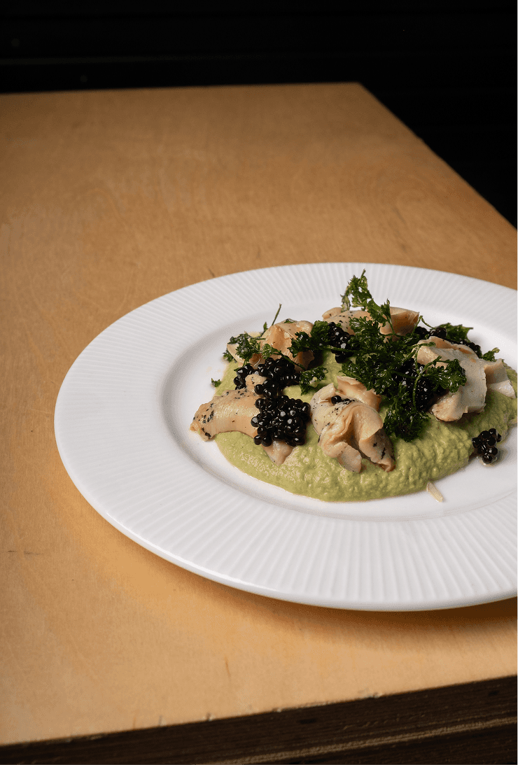 Plat du ambre sur le coin d'une table. Bourgots, chou vert et persillades dans une assiette blanche.