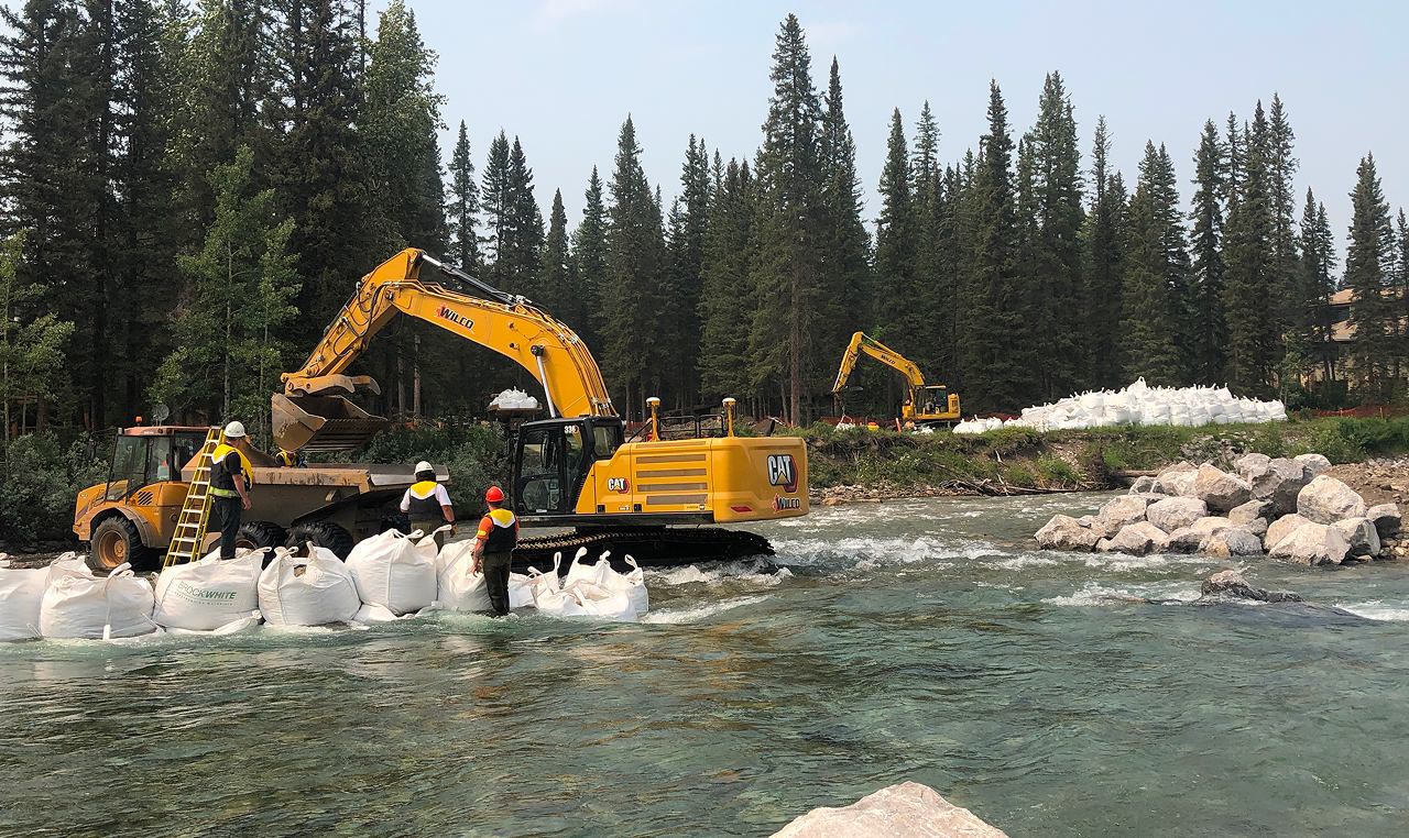 Construction crew building sandbag cofferdam for in-stream work isolation at Bragg Creek