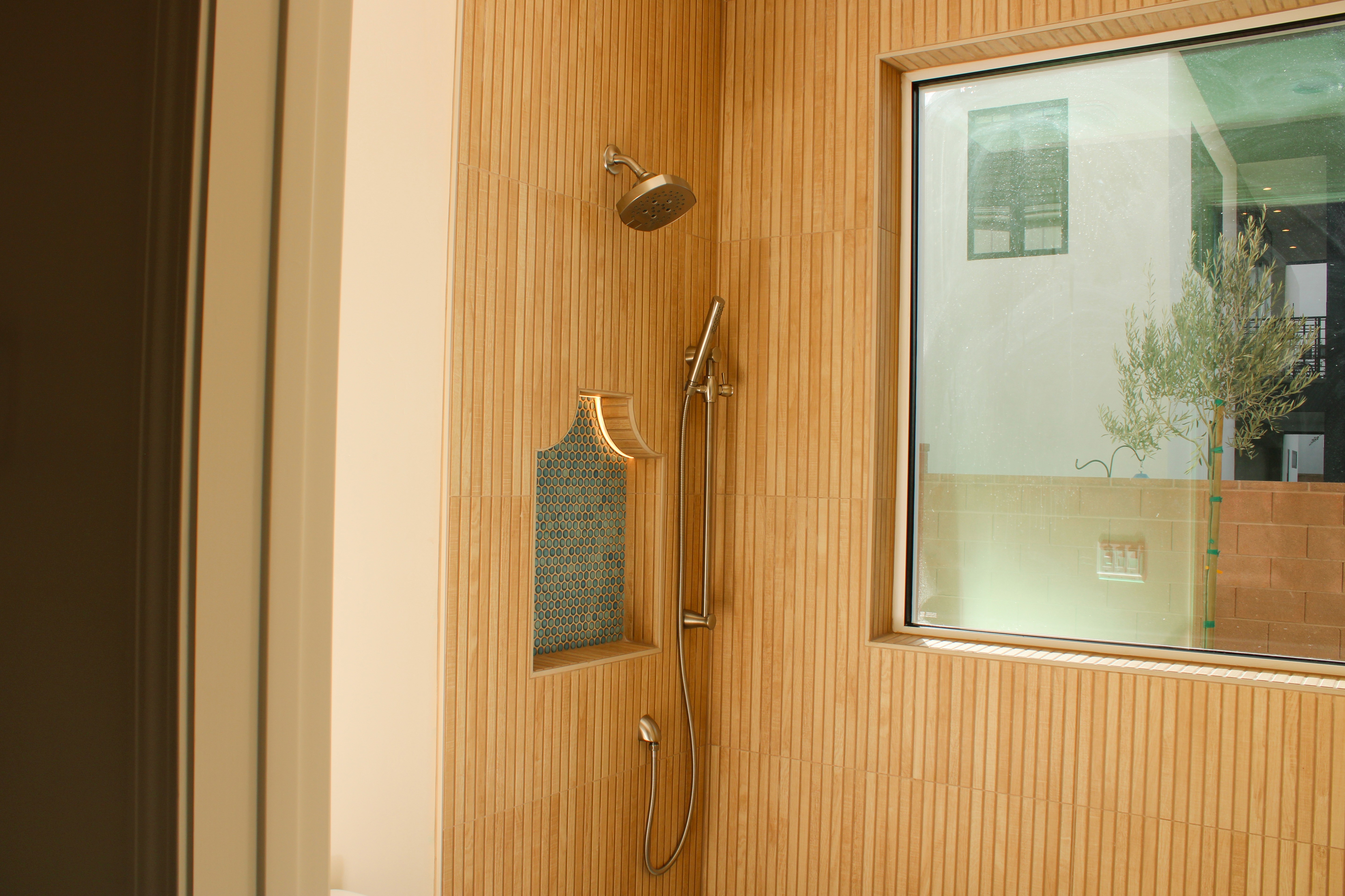 Walk-in shower featuring decorative tiles and an arched niche for toiletries in a St. George, Utah home.