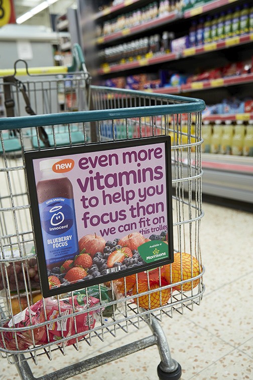 Close-up of hand holding pink ice cream cone against pastel background
