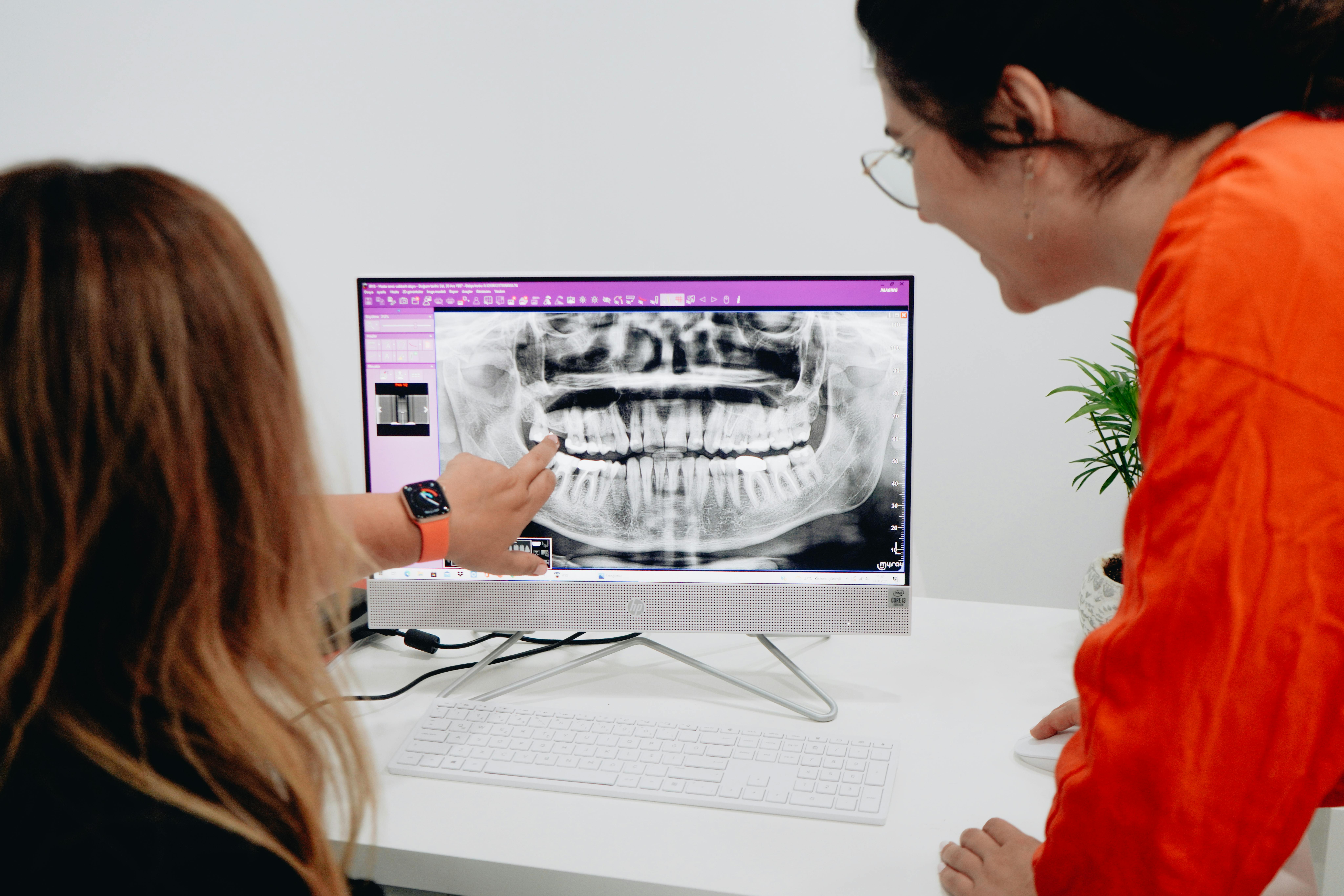 Two woman looking at screen showing xrays of teeth