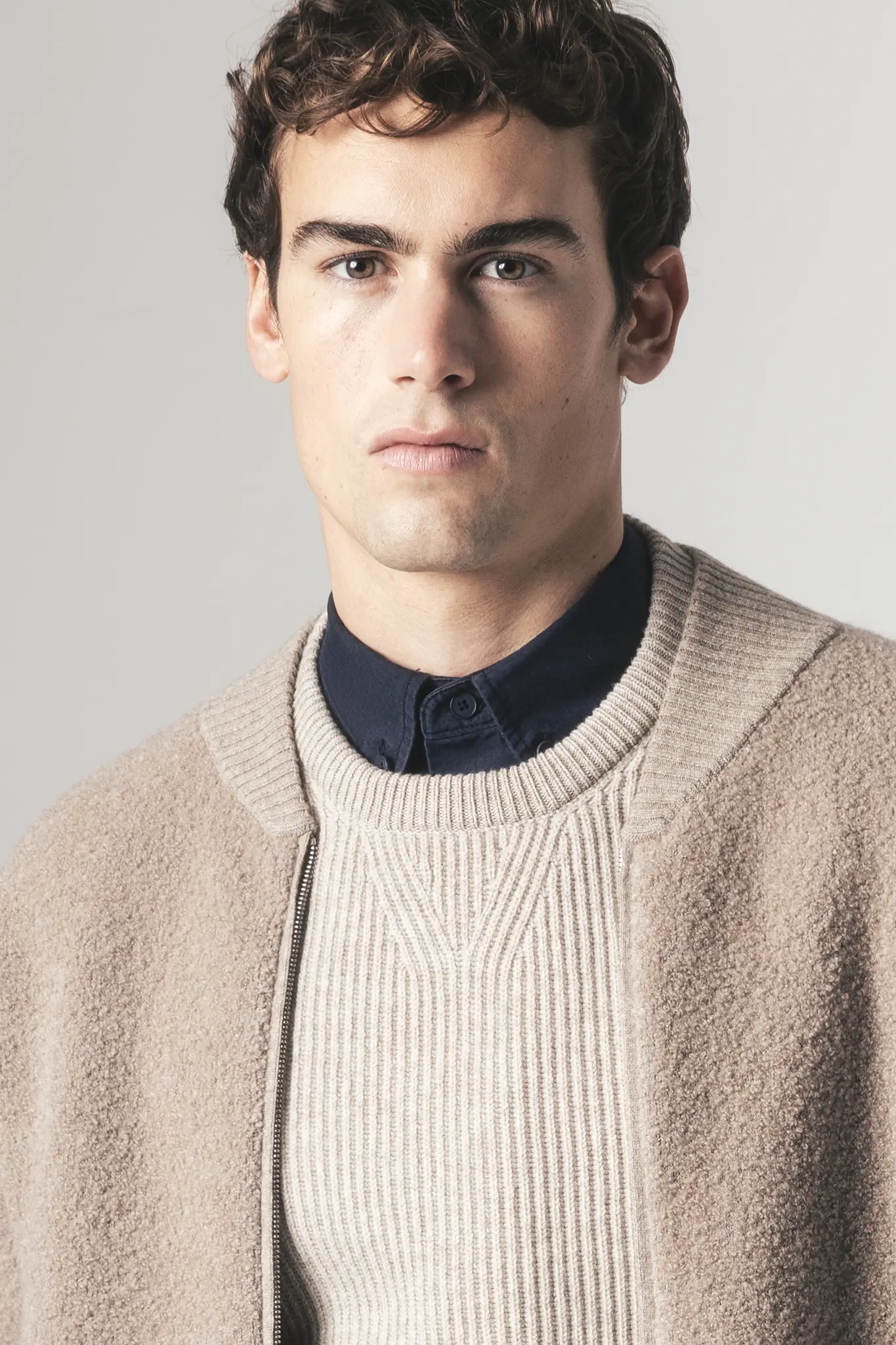 Man wearing beige cashmere sweater and jacket layered over navy shirt – Aida Barni FW25/26 collection.