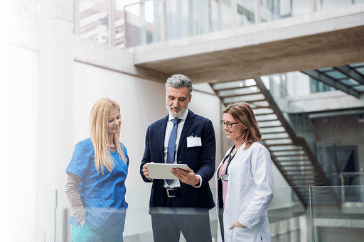 A nurse, a man and a doctor look at a tablet