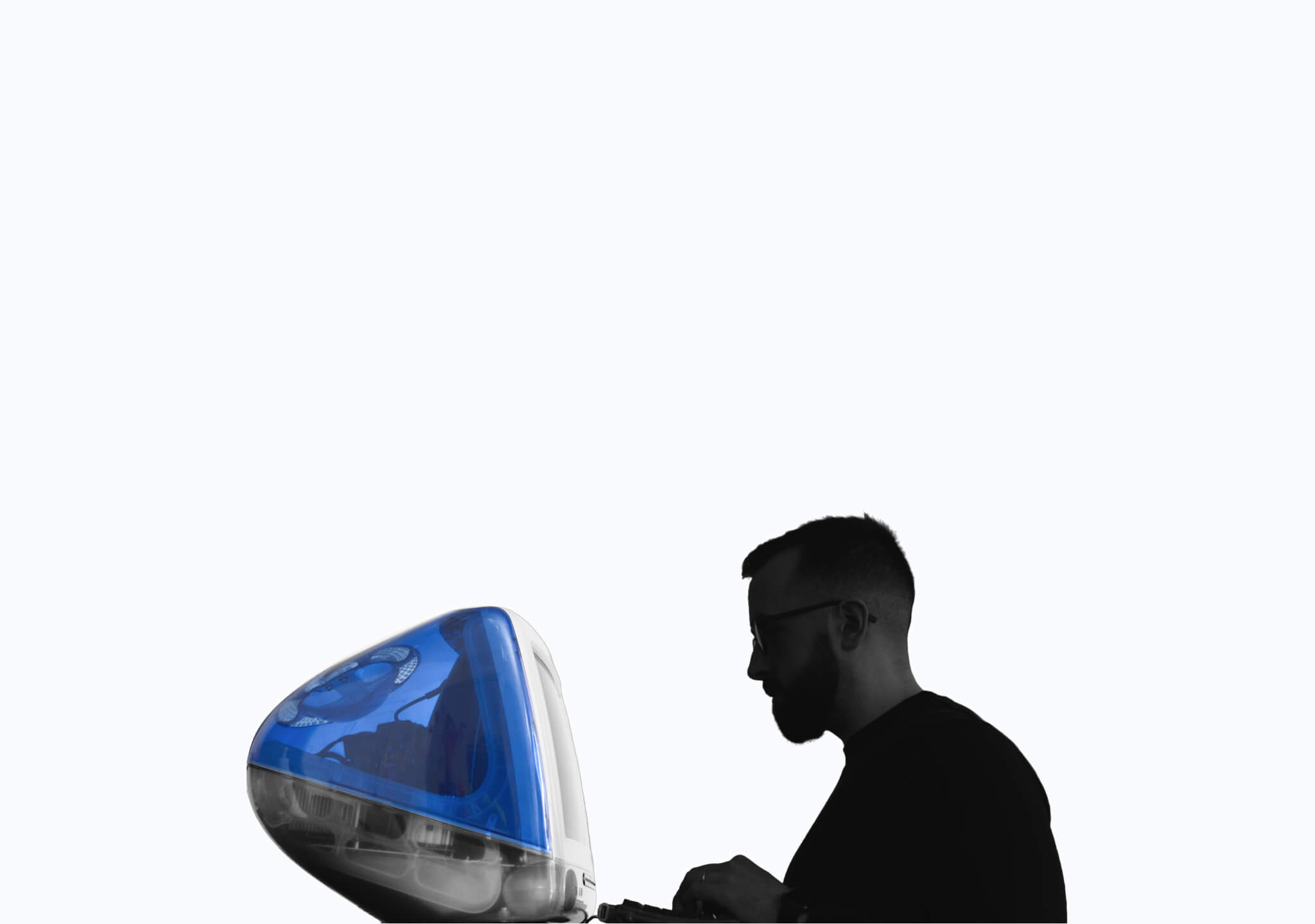 A photo of cormac, positioned from the side, facing a iMac G3 computer.