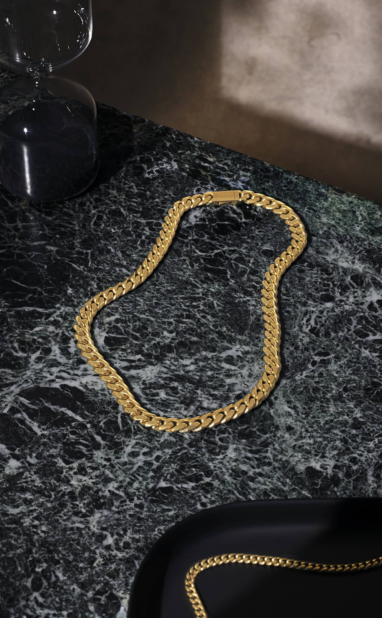Elegant gold chain necklace on a marble surface.