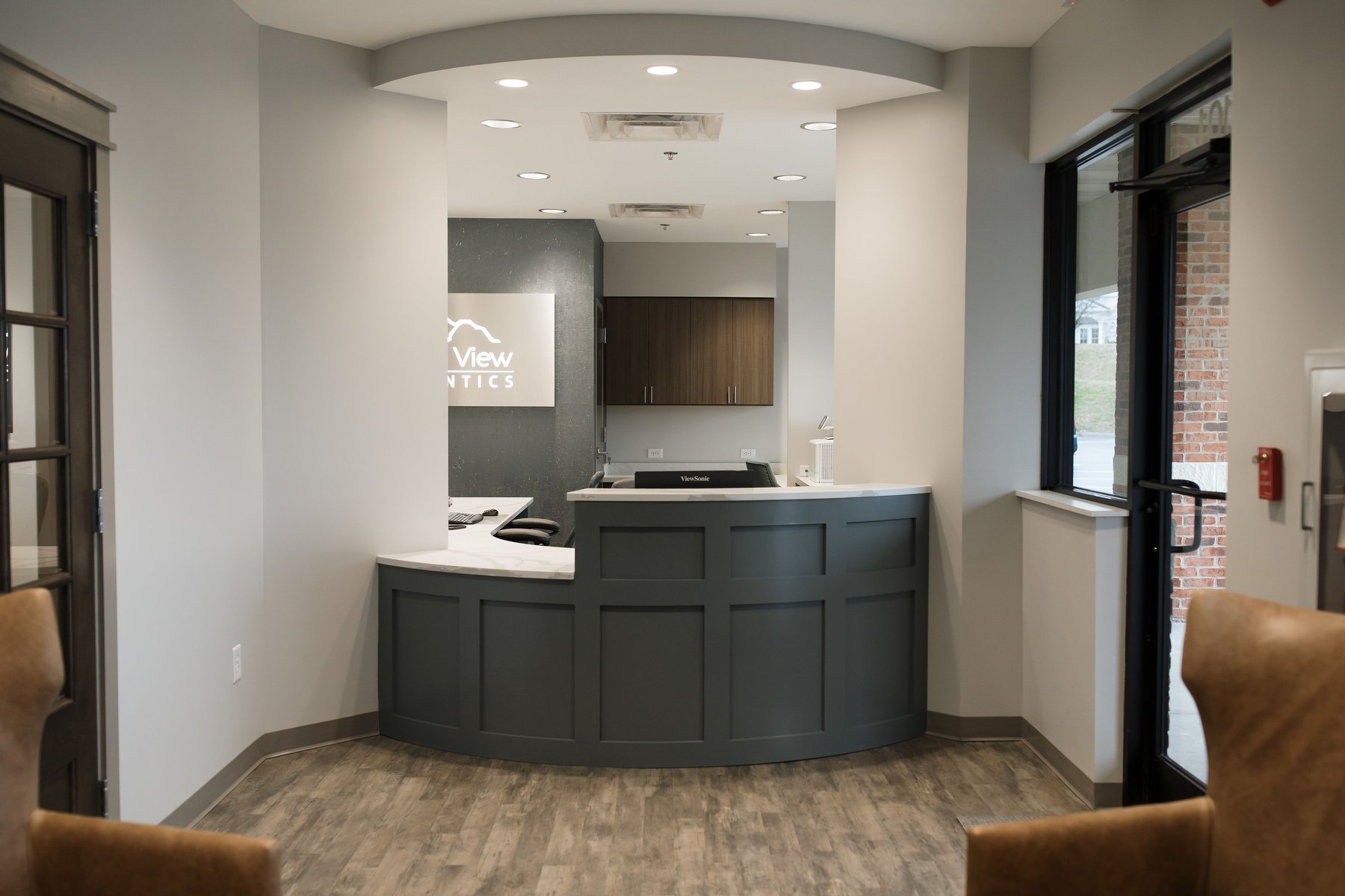Modern reception with a curved counter, stainless steel, and neutral colors throughout.