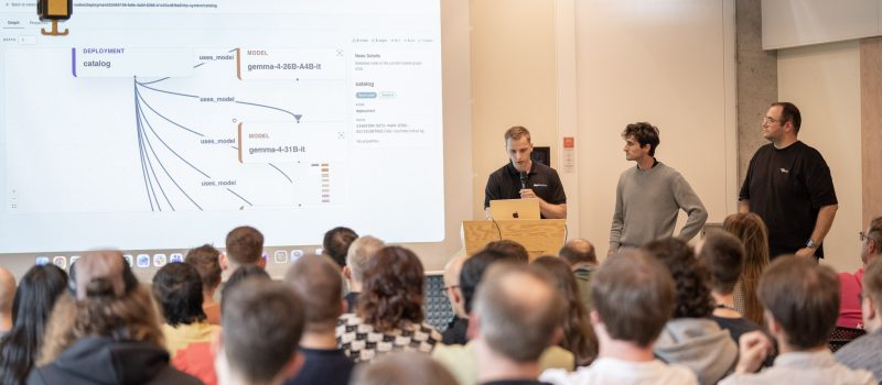 Three speakers presenting the Naira and Thalamus integration to a full room, with the model catalog graph projected on the screen behind them