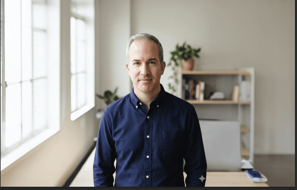 Close-up of a person looking down in soft light, wearing a small hoop earring