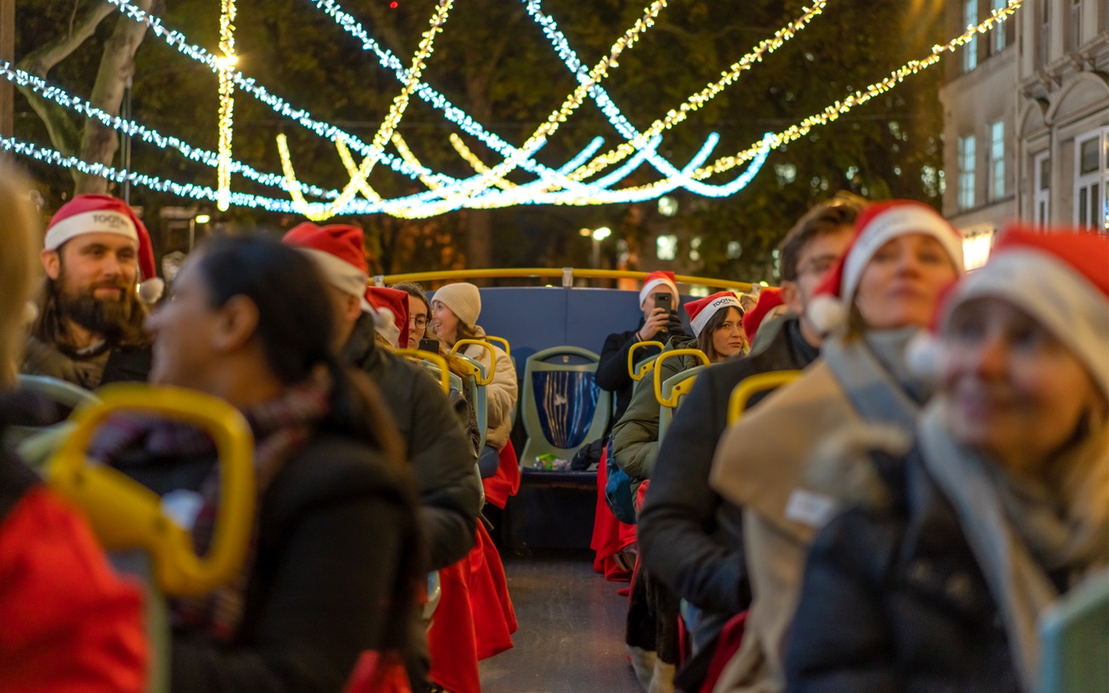 Utazók Mikulás sapkában egy Tootbus járaton élvezik London karácsonyi fényeit.