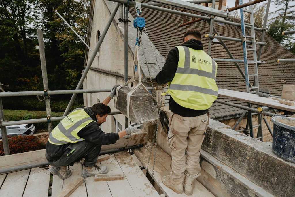 Two men lifting a cotswold stone coping into place