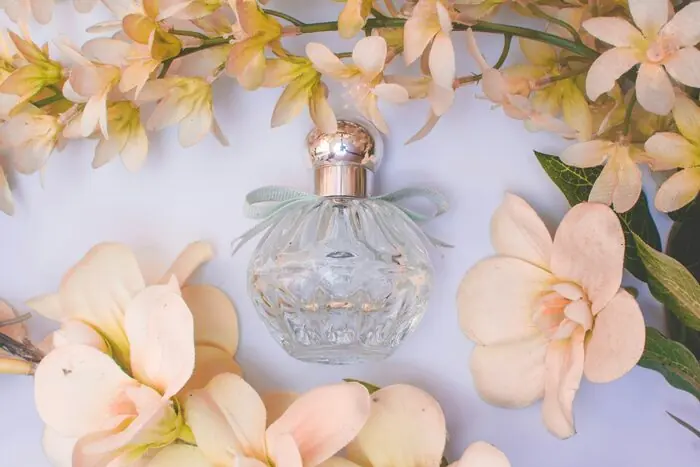 A cut-glass perfume bottle set among pale cream and pink orchid blooms