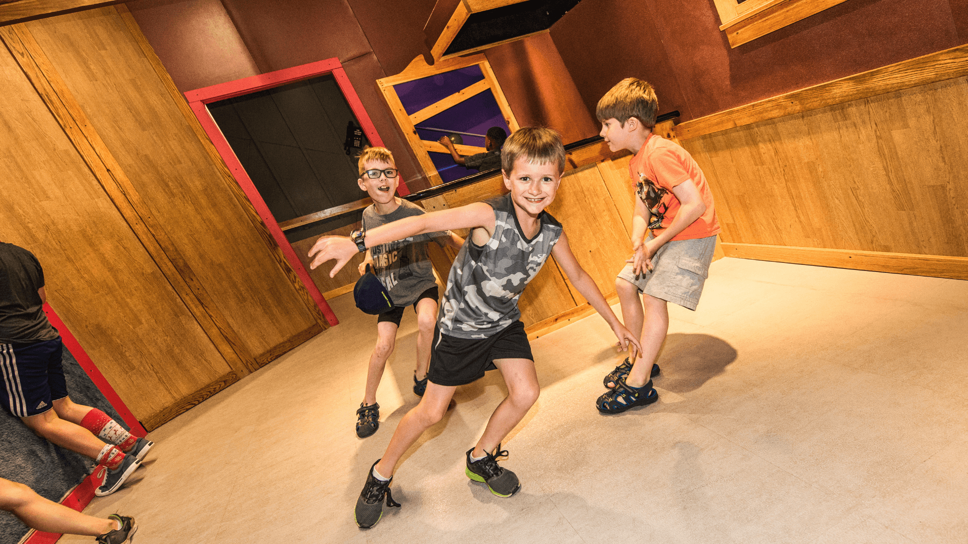 Three young boys test their balance in the Distorted Gravity Room. 