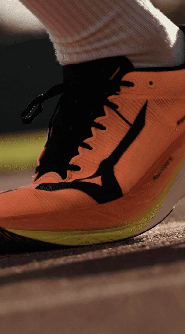 Bride sitting on ground against wall, groom standing nearby