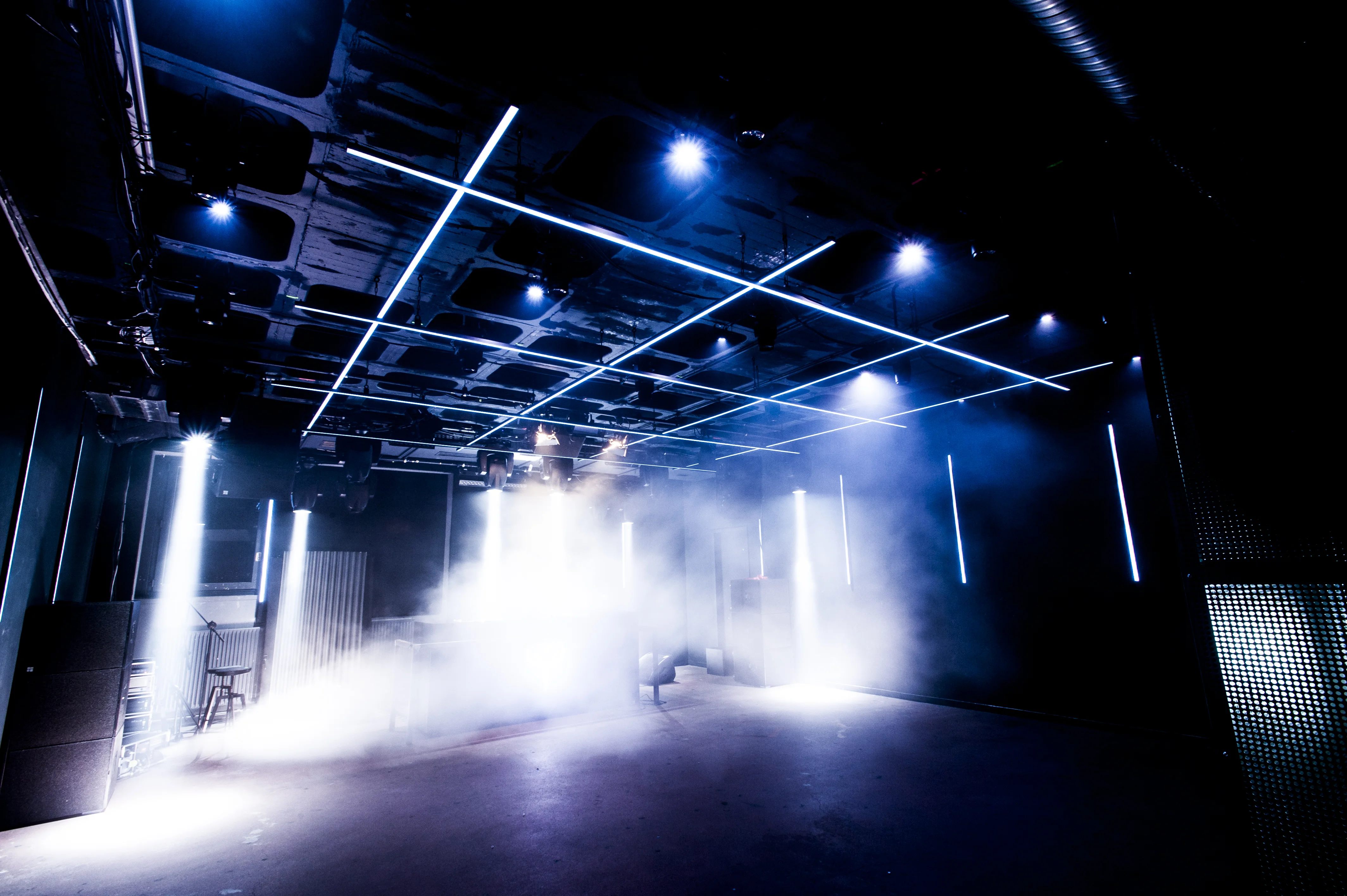 Fog-filled stage room at the Jägermeister Night Embassy with a grid of white LED light lines across the dark ceiling.