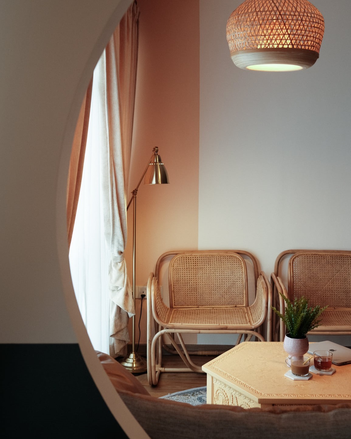 Scandinavian-inspired lounge area with rattan chairs, warm lighting, and sheer curtains by Persqft Singapore