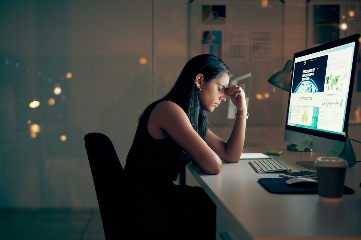 A person using a computer at an office desk with equipment.
