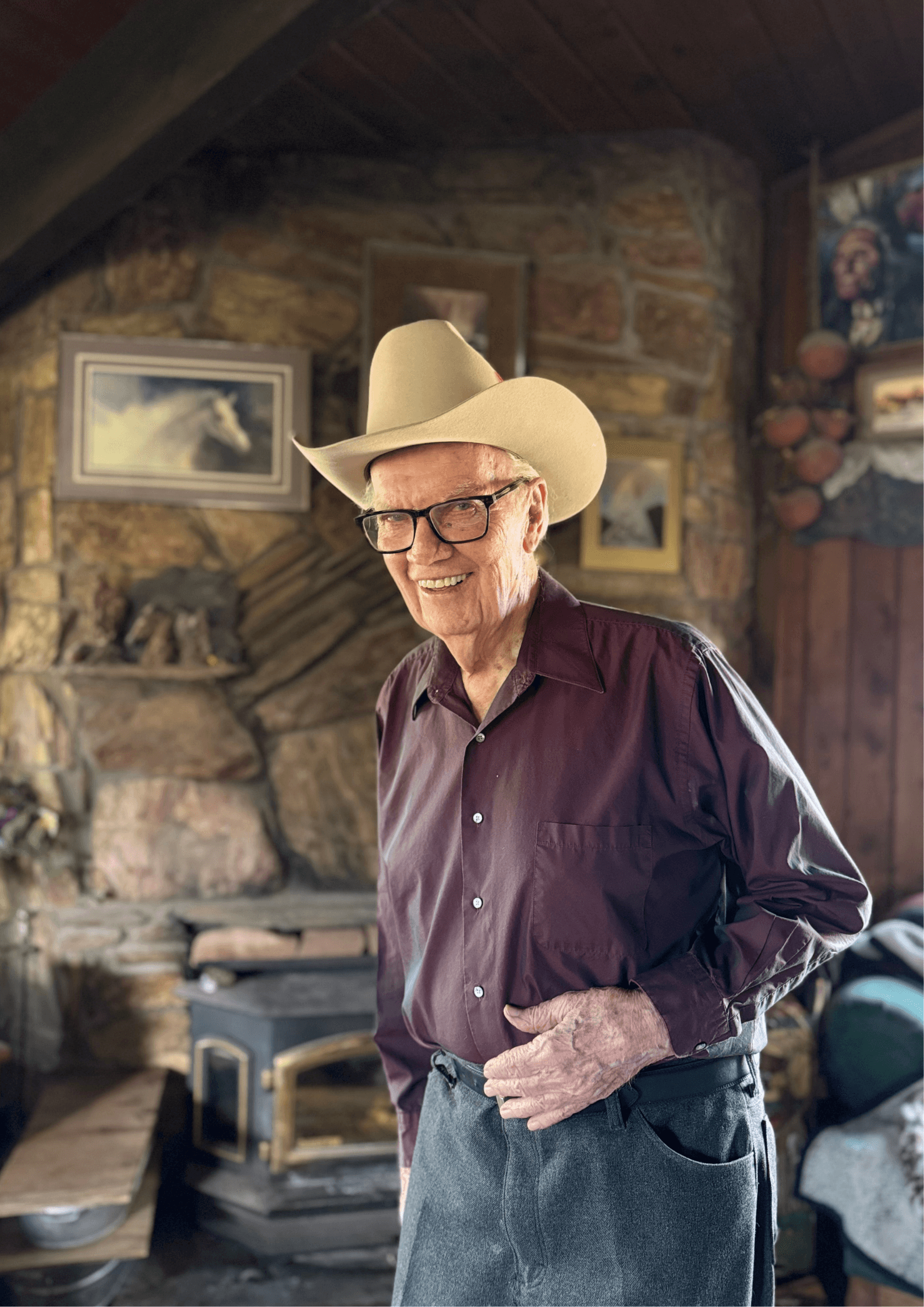 Middle-aged man in glasses working on laptop beside a window with a relaxed posture.