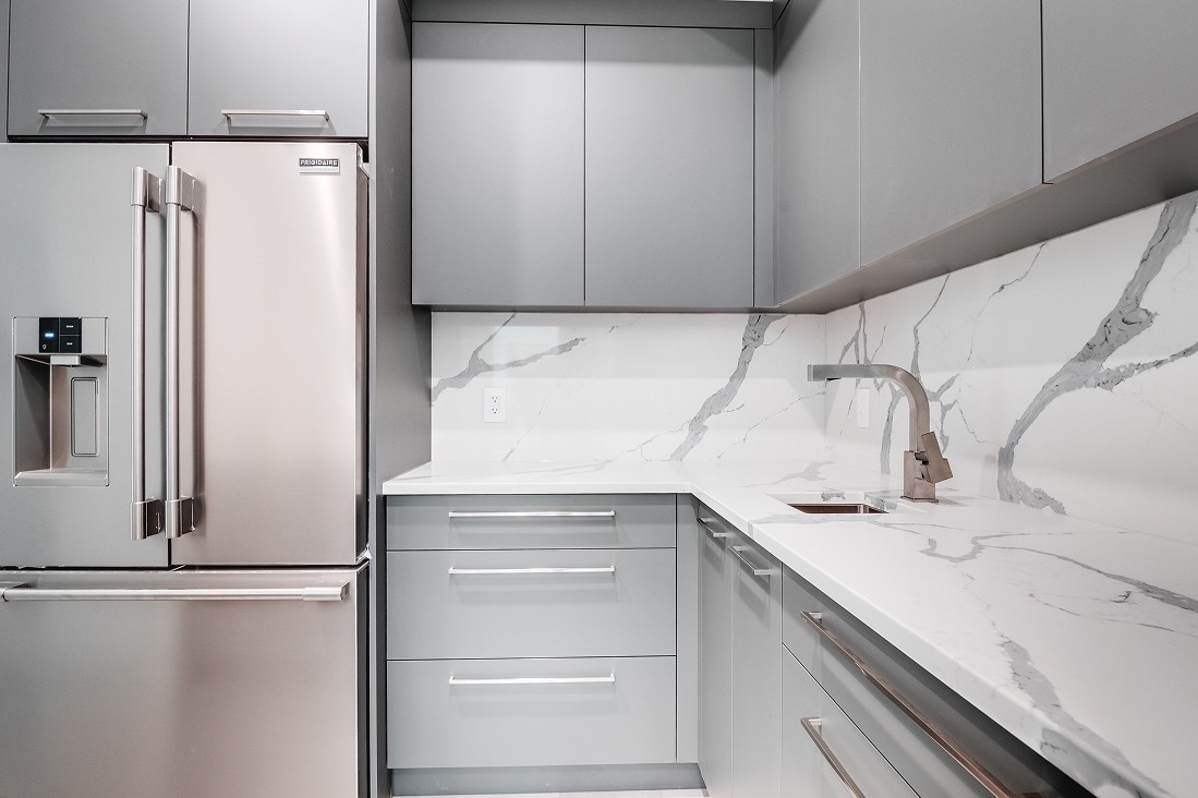 Angled kitchen view with built-in fridge and white counters