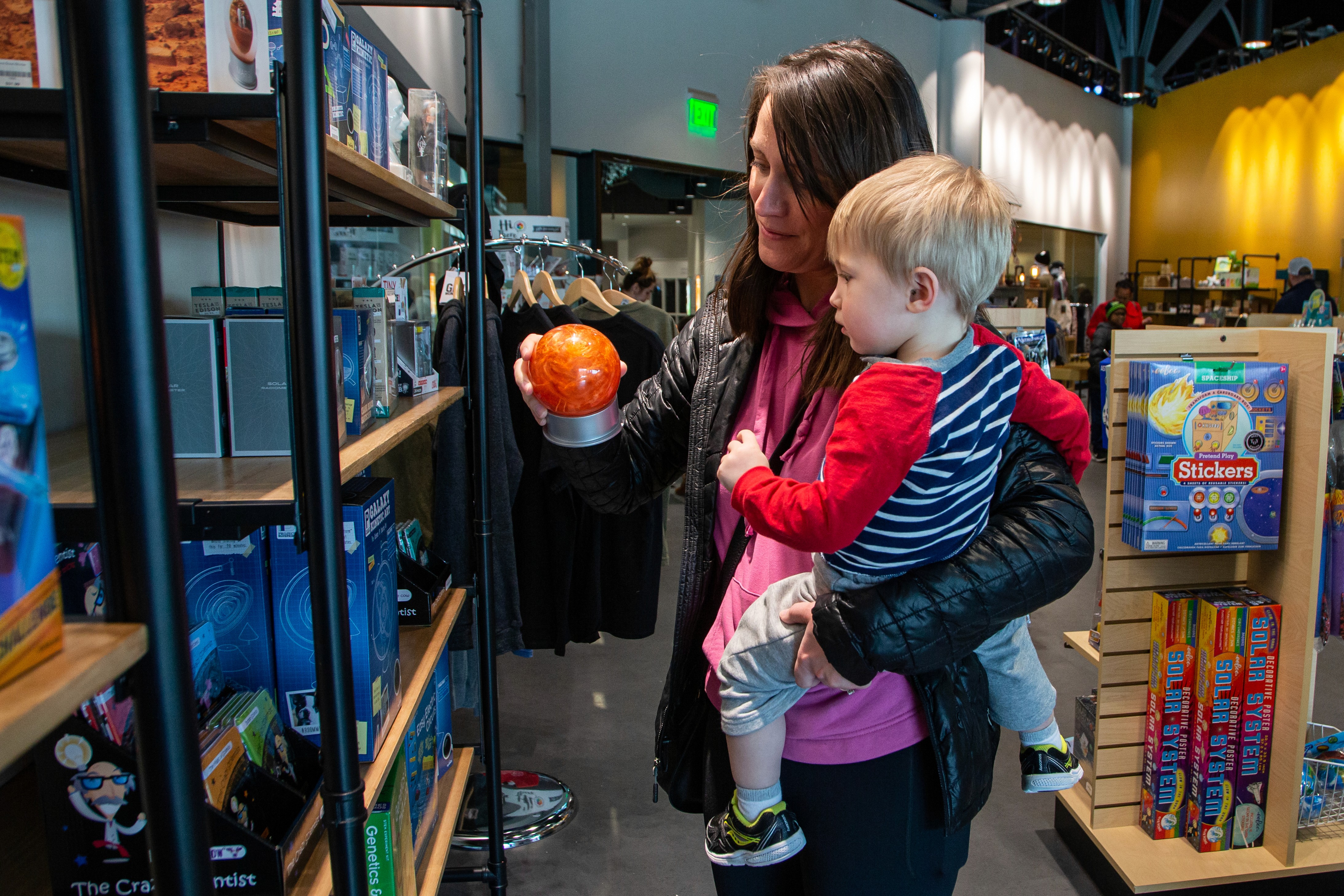 A mom and son picking out an item at the Science2Go gift shop.