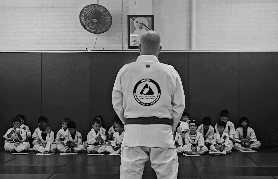 Coach kneeling on the mat during a kids' Jiu Jitsu session