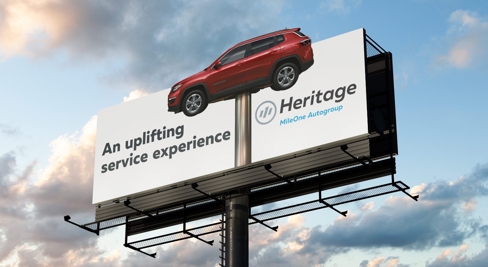 A billboard displays a red SUV positioned upright above the text "An uplifting service experience" and "Heritage MileOne Autogroup" with a logo, against a cloudy sky.