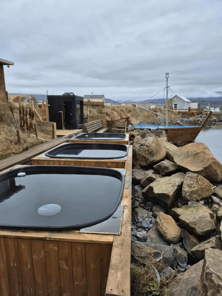 Rectangular wooden hot tubs built into the rocky seaside shoreline.