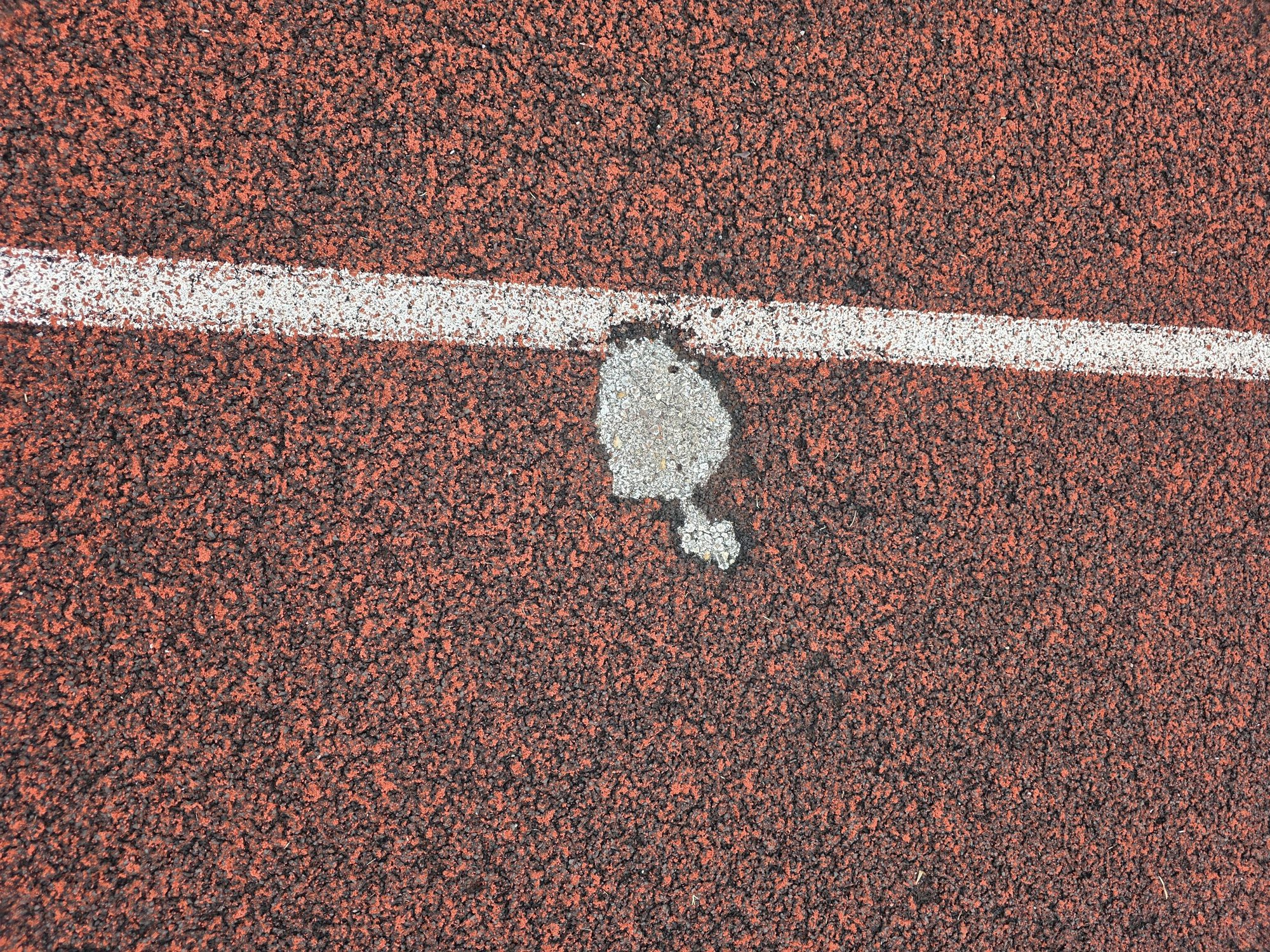 Repaired spot in the old track surface beside a lane line at George County High School in Lucedale, MS