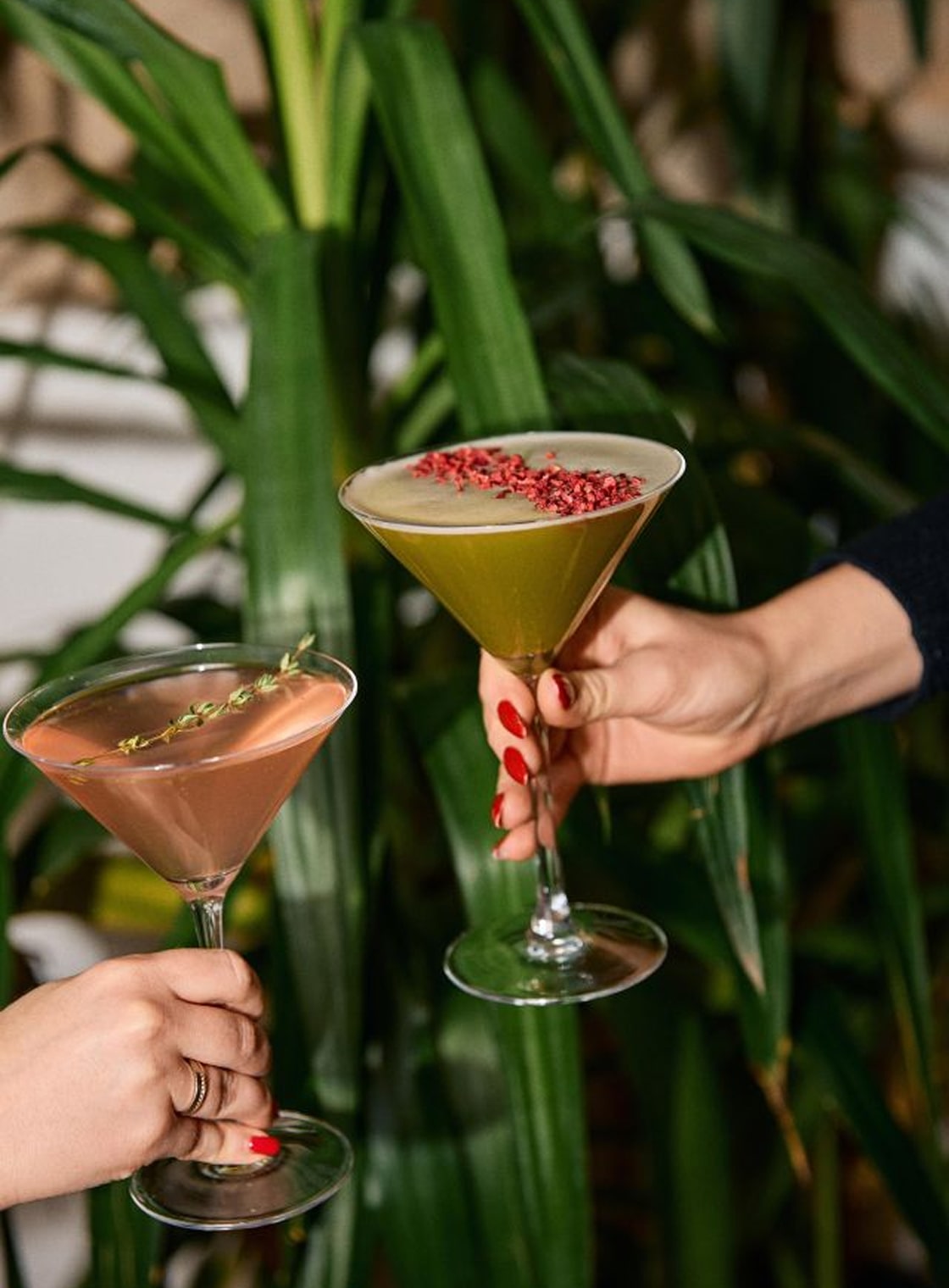 Two people holding green cocktails