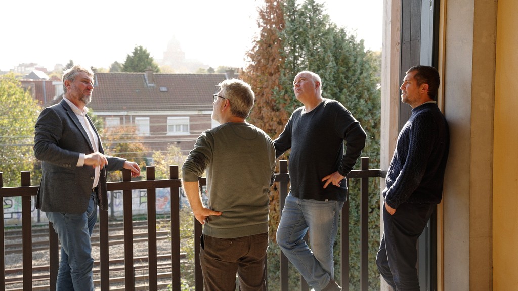 Four men discussing on a balcony