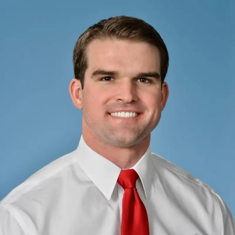Man in white shirt and red tie smiling