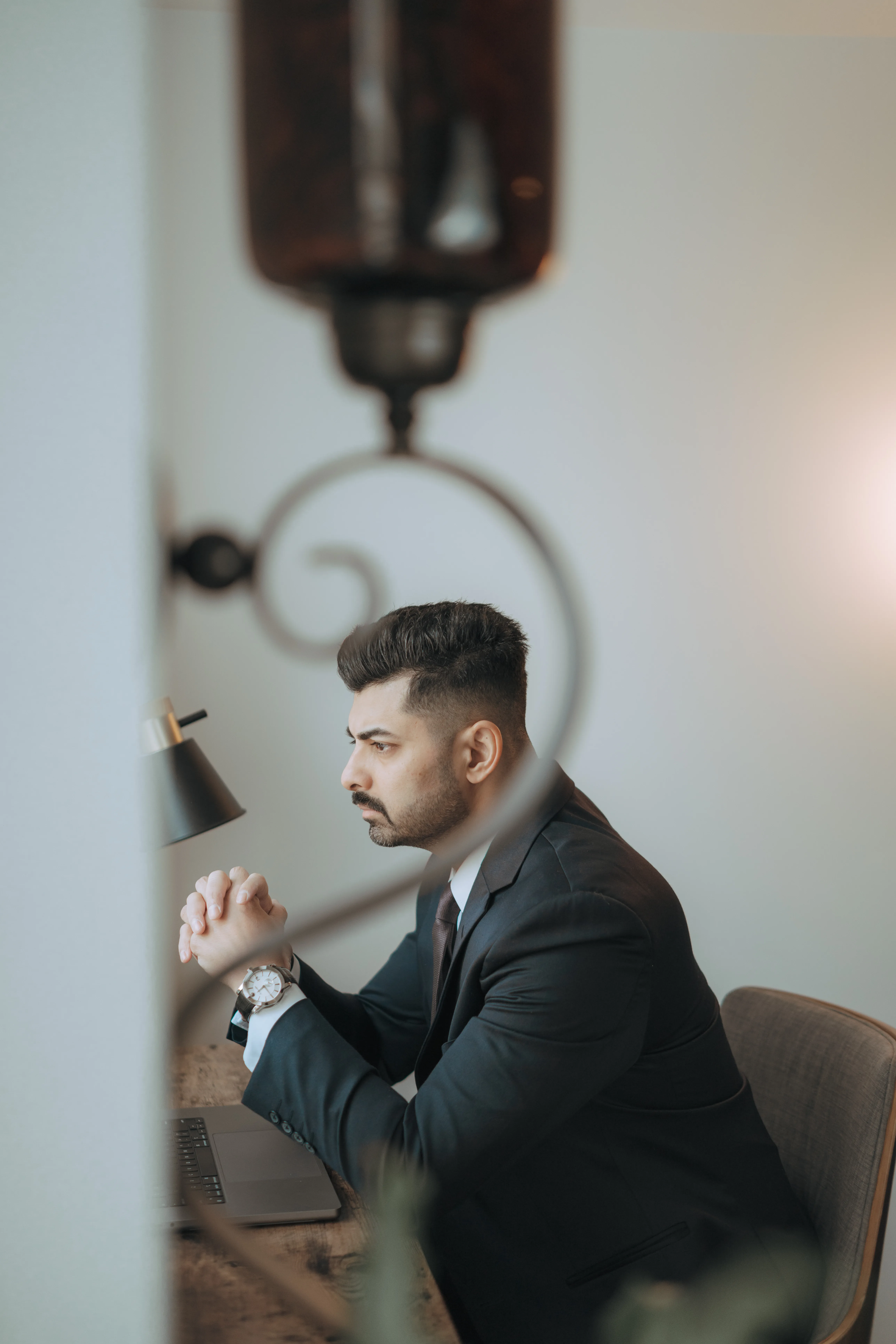 Male scientist in a white lab coat standing confidently in a modern hydroponic lab with pink grow lights and rows of leafy greens.