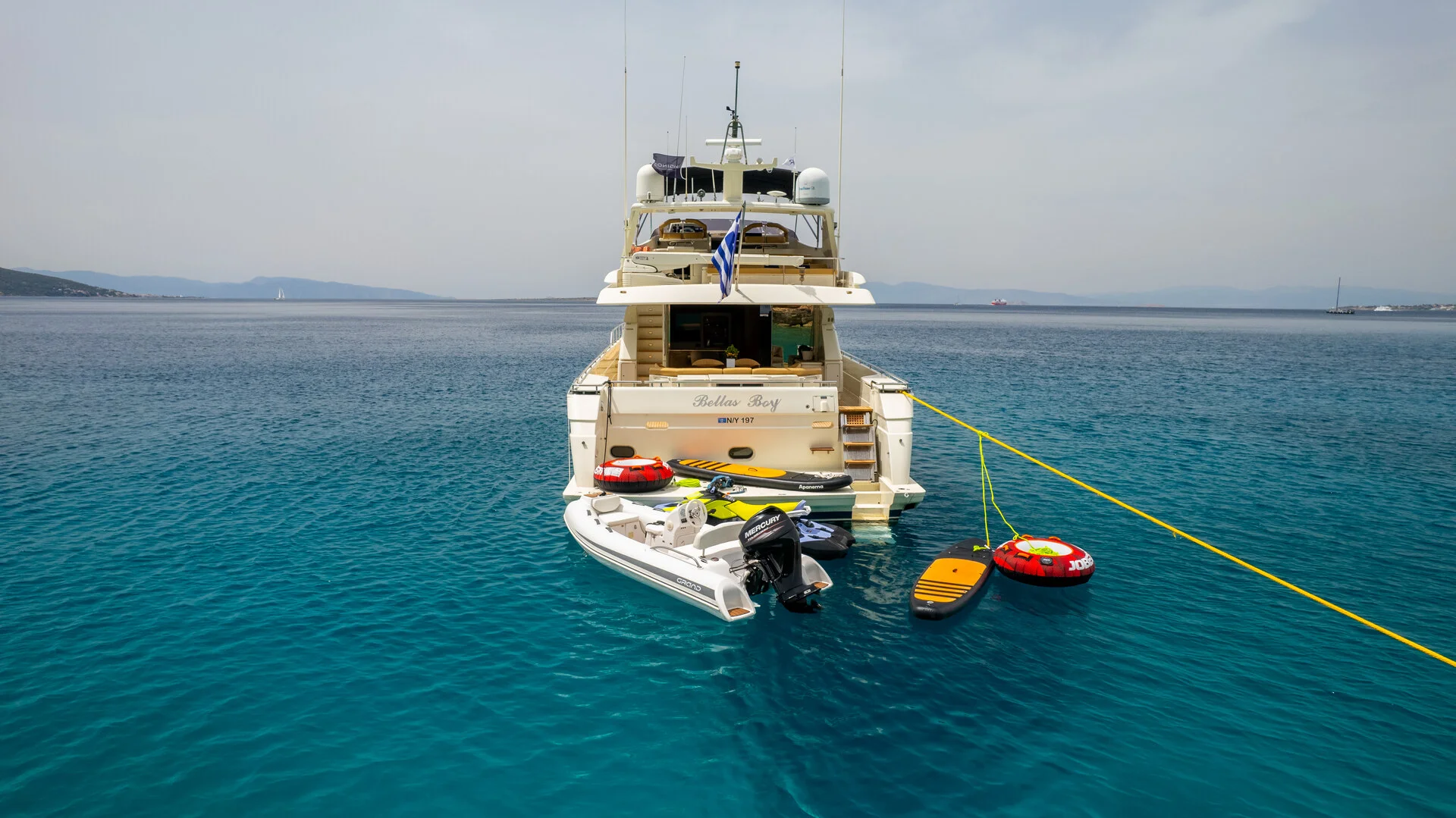 White Rock 36 speedboat with captain at helm cruising calm blue waters near Paros coastline with hills in background.