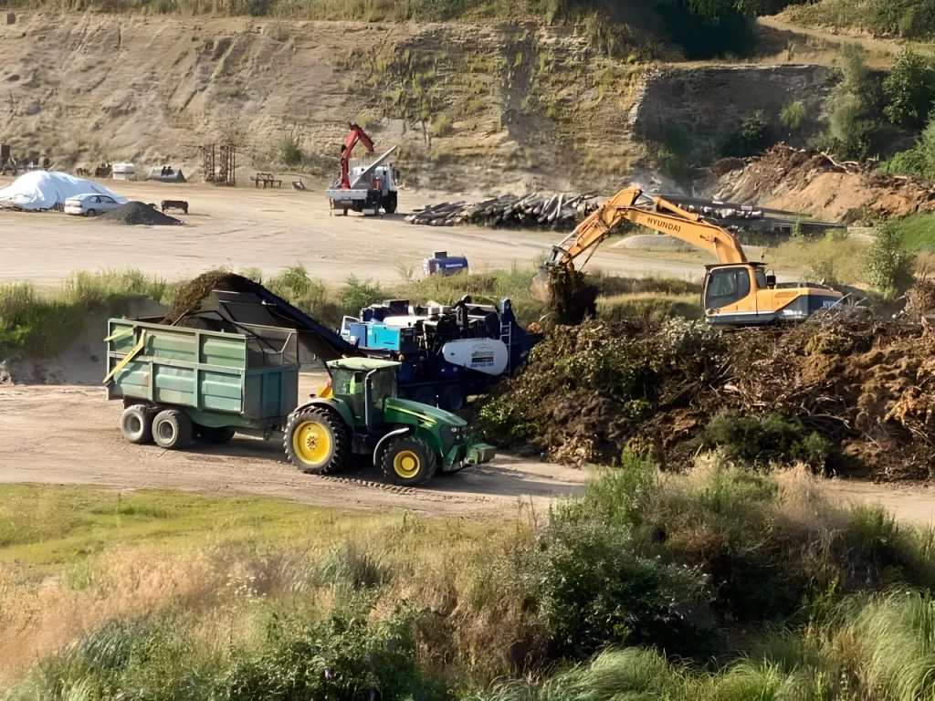 Excavator loading green waste into a trailer at Wilson Sand yard in Matamata