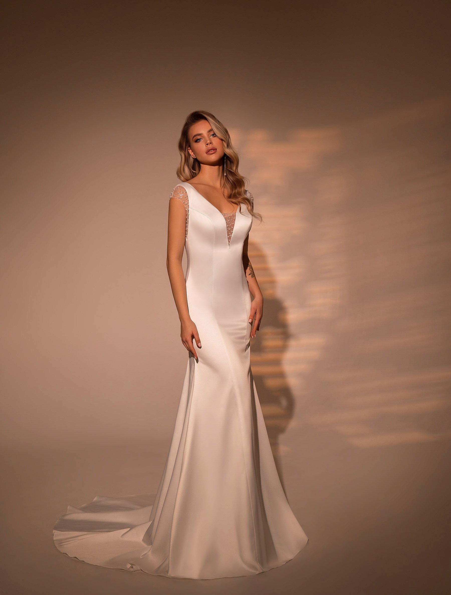 Elegante minimalistische trouwjurk met sleep en pareldetails op de schouders