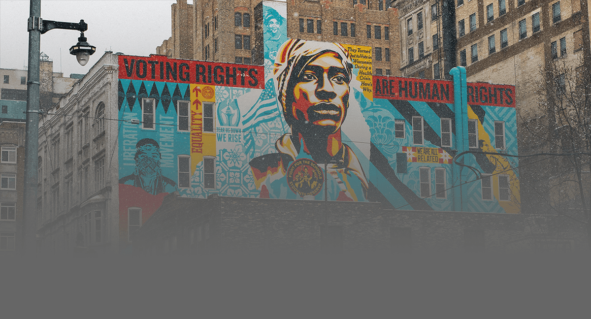 A colorful mural depicting a face surrounded by vibrant patterns, set against an urban background.