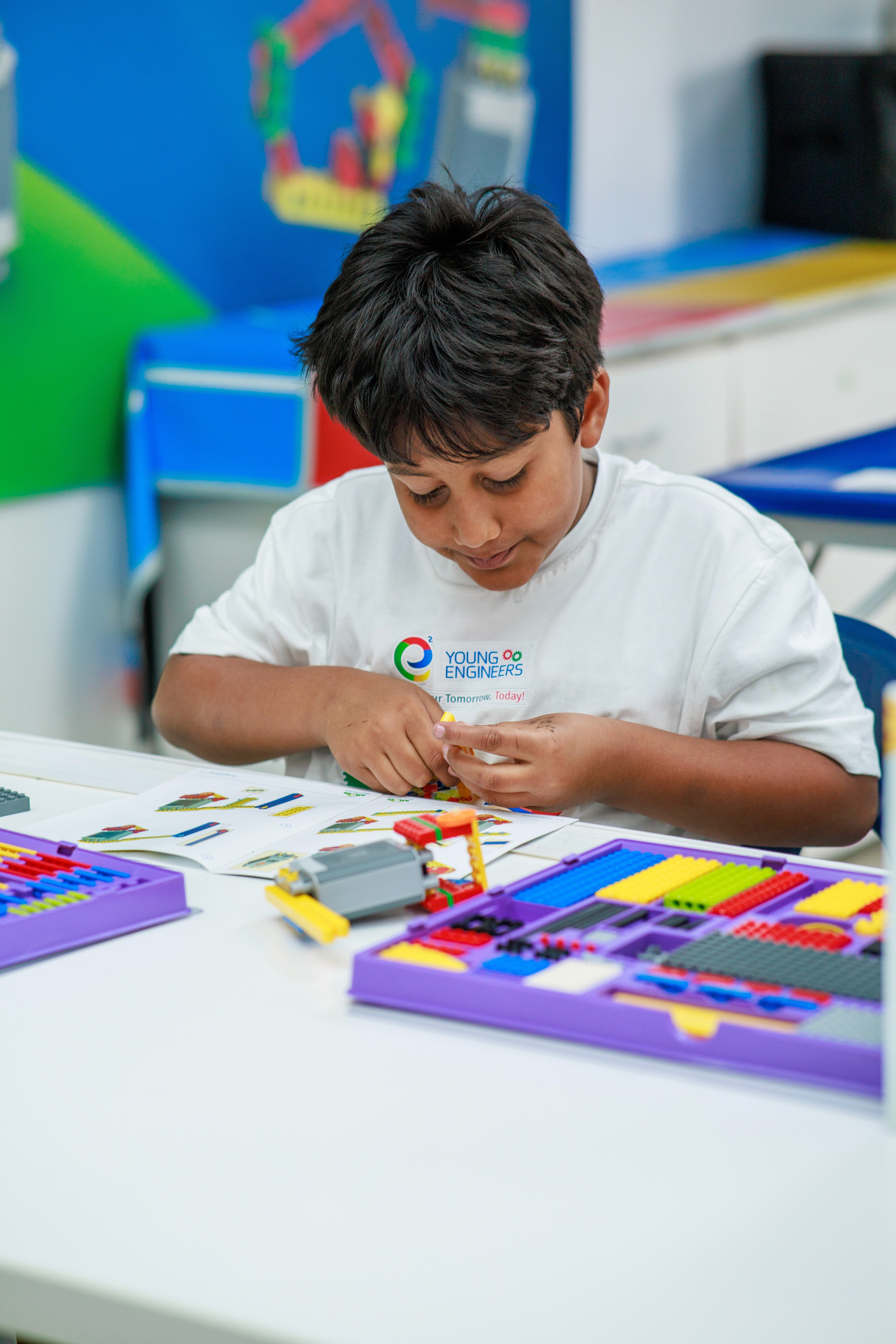 Enfant concentré assemblant un robot avec des blocs LEGO lors d’un atelier Young Engineers à Montréal.