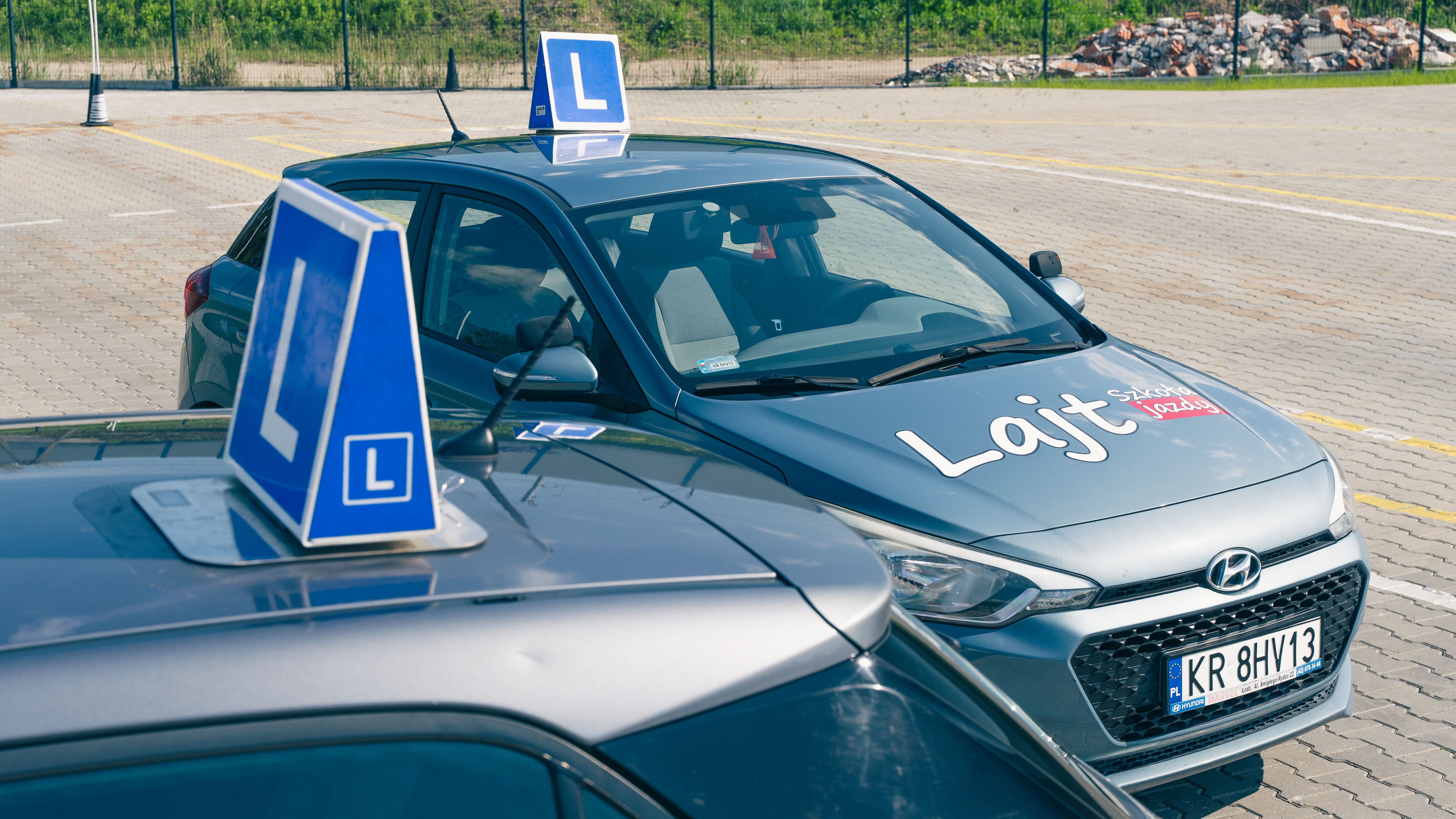 Samochody OSK Lajt Kraków ustawione na placu manewrowym z widocznymi tablicami L