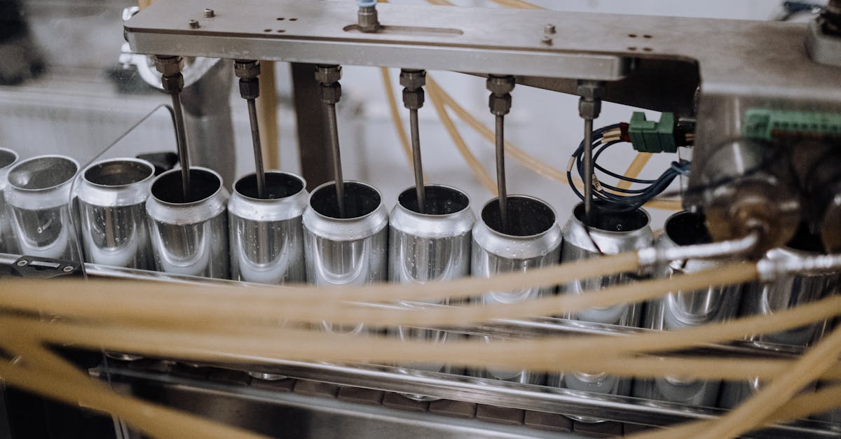 Close-up of automated machinery on a beverage can filling production line indoors.