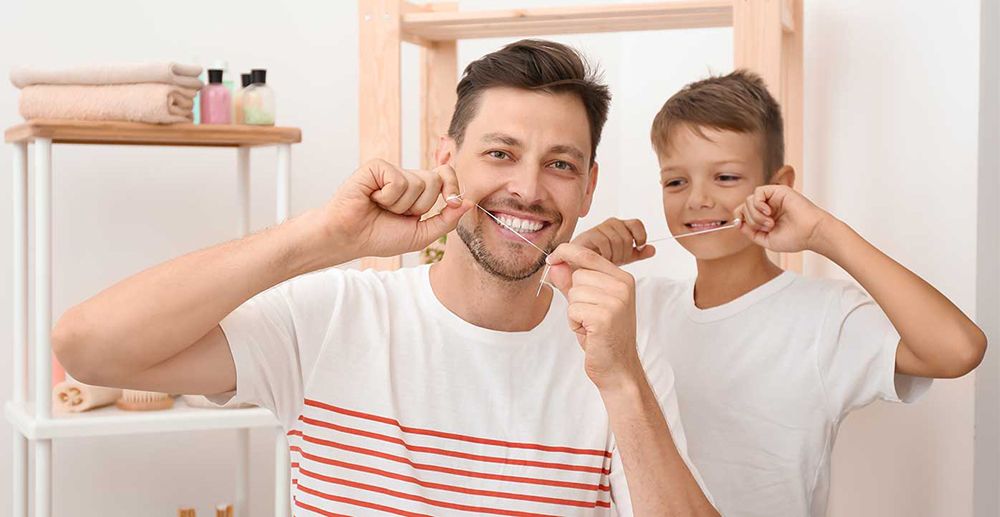 Father and son using dental floss