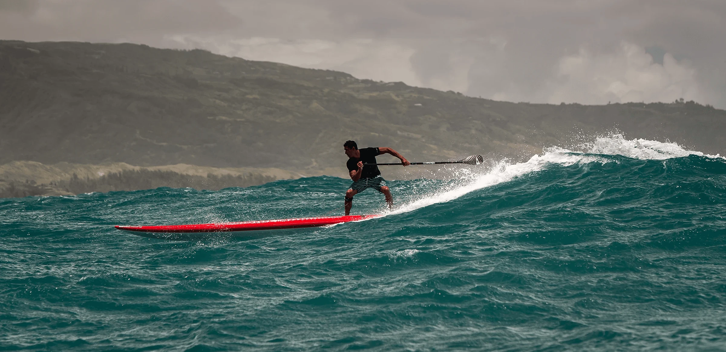 Stand-up paddleboarder riding an ocean wave