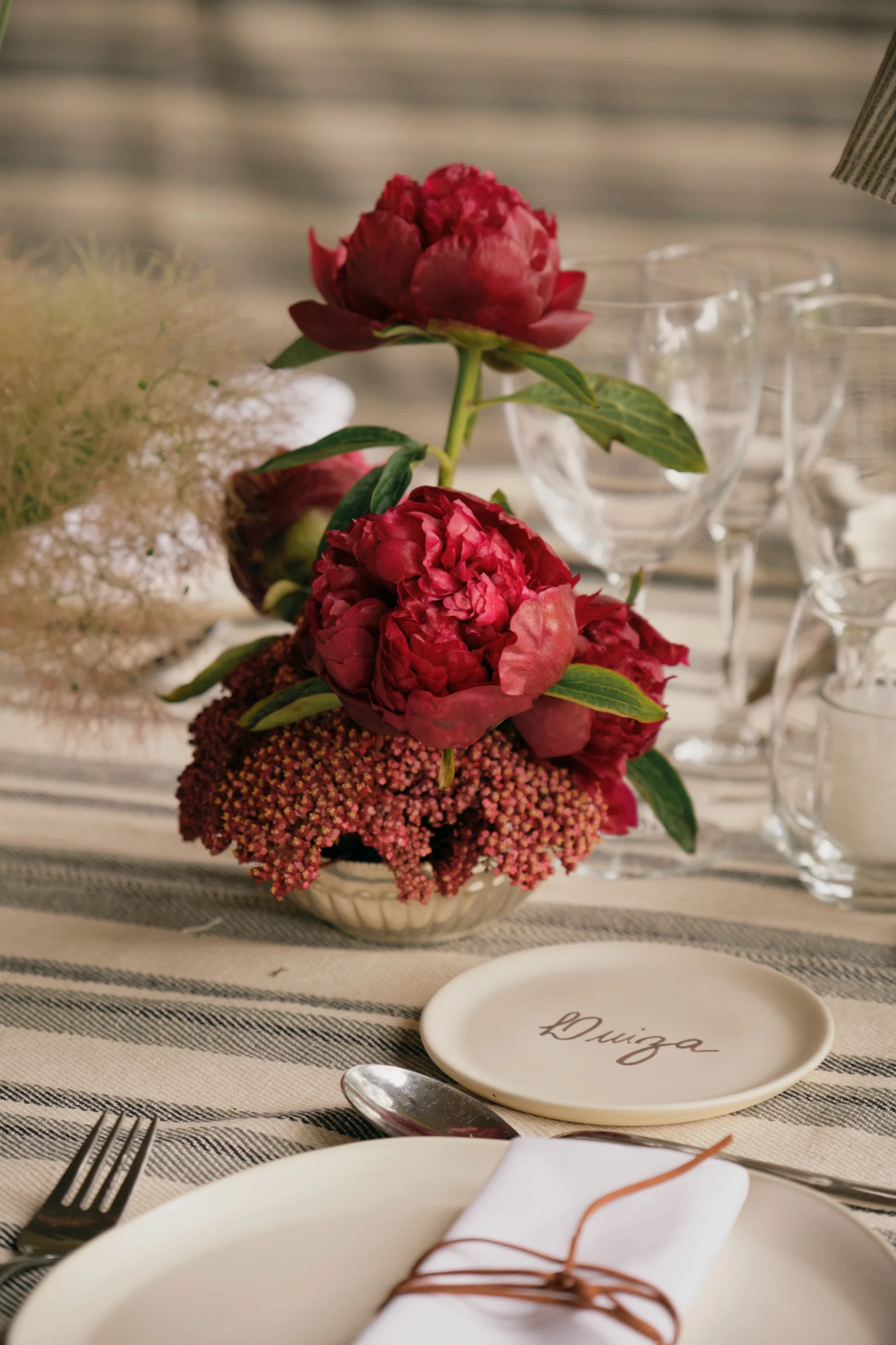 Primer plano de centro de mesa con peonías fucsia y rosas.