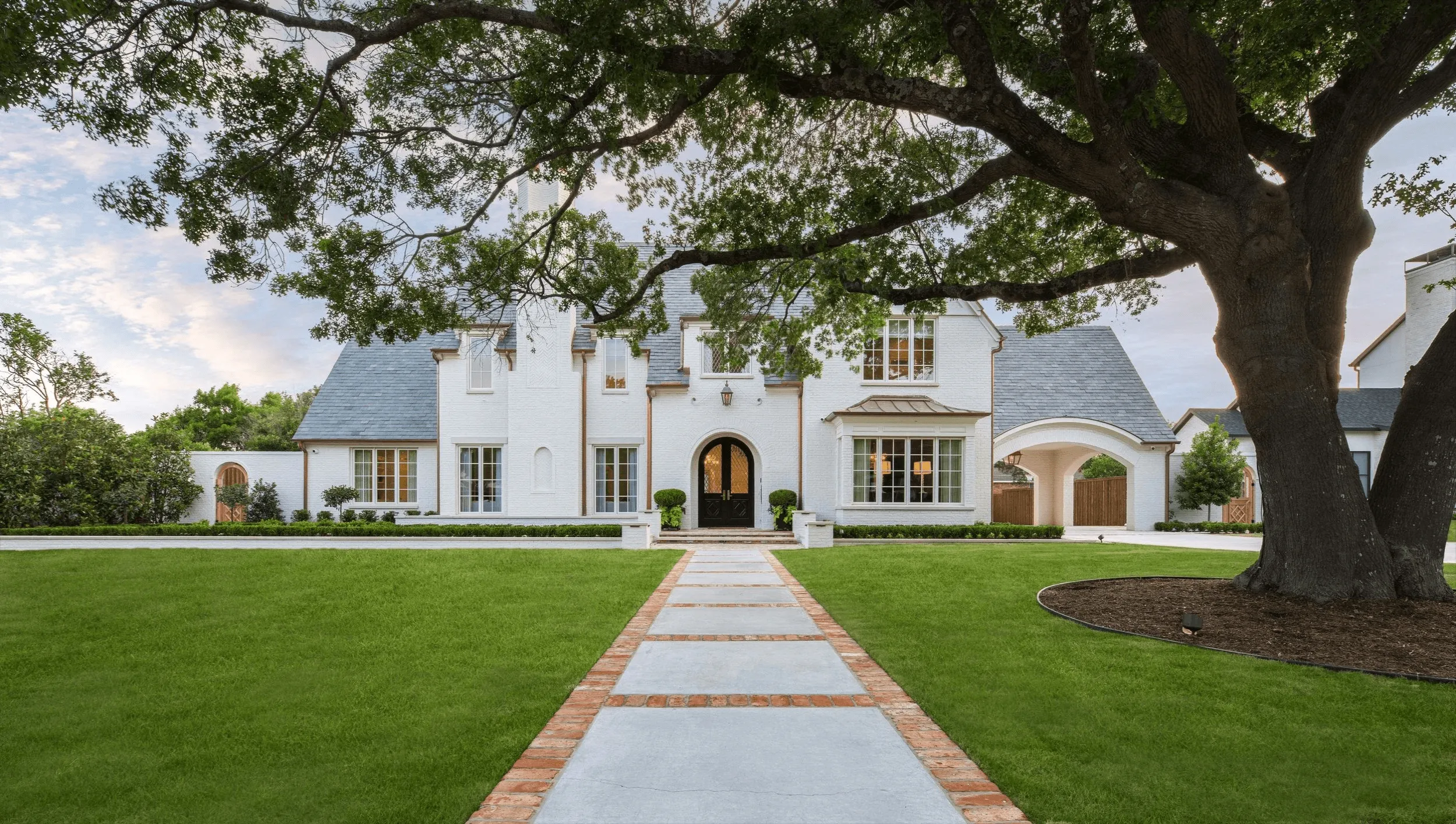 Luxury front yard landscape design with geometric limestone and brick walkway at French country home in Dallas Park Cities